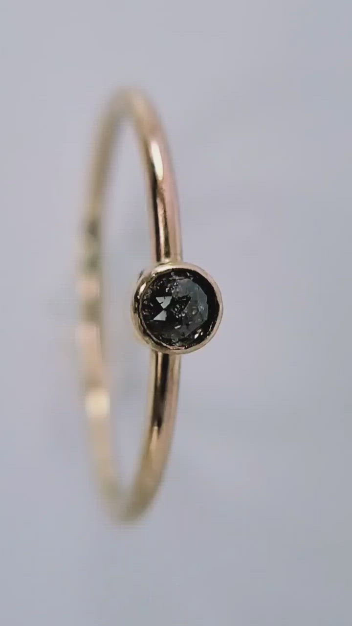 Light shining off the star shaped pattern on a highly included salt and pepper 14k gold diamond engagement ring.